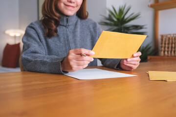 Closeup image of a young woman writing on a letter and envelopes