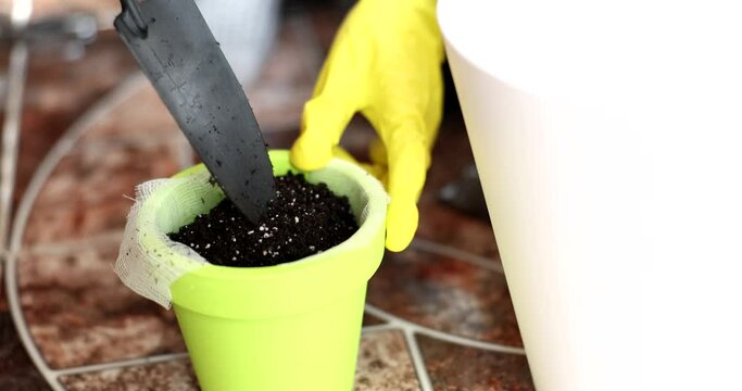 Gardener pouring earth into pot with spatula closeup 4k movie slow motion. Planting houseplants concept