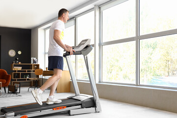 Sporty mature man training on treadmill at home