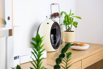 Modern coffee machine with croissants on wooden table in office