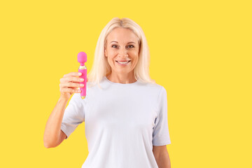 Mature woman with vibrator on yellow background