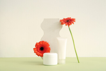 Composition with cosmetic products, plaster podium and beautiful gerbera flowers on color background