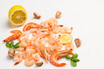Shrimp, tiger prawns scattered on white background. Leaves of green basil, lemon, garlic.