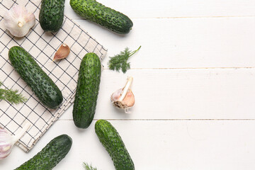 Fresh cucumbers, garlic and dill on white wooden background