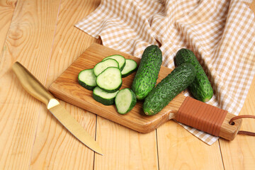 Board with fresh cucumbers on wooden background