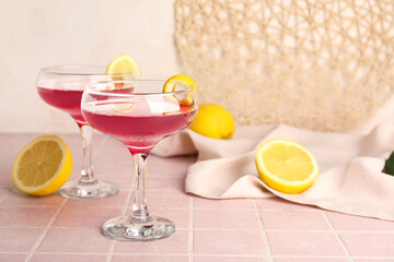 Glasses of Cosmopolitan cocktail with lemon on pink tile table