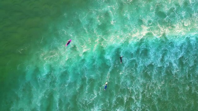 Seen from above, surfers paddled with the waves breaking, leaving a trail of foam, Cascais,Portugal- top down, drone shot