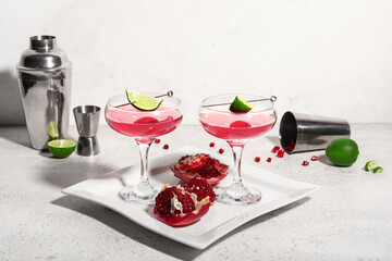 Glasses of Cosmopolitan cocktail with lime and pomegranate on white background