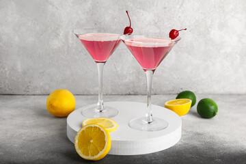 Glasses of Cosmopolitan cocktail with cherries and lemon on grey background