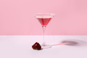 Glass of Cosmopolitan cocktail with pomegranate on colorful background