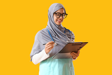 Young Muslim doctor with clipboard on yellow background