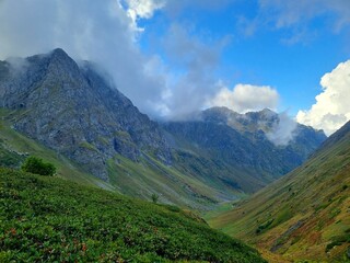 Snow-Capped Mountains with Green and Dry Grass, Clouds, and a Stunning Sky
