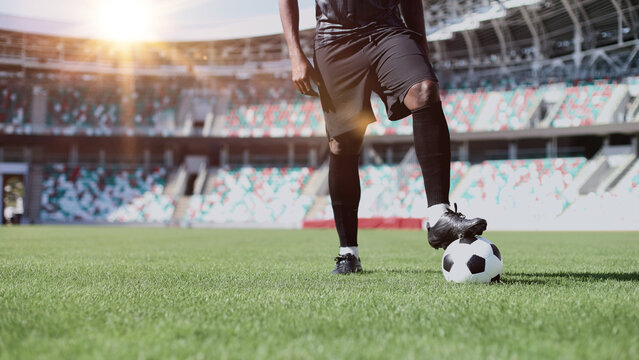 African American man playing football on the stadium field. A man runs with a soccer ball across the field.