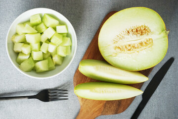 Sliced ​​juicy melon on a wooden board on a gray background