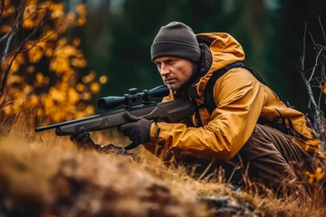 Fotobehang Hunter during hunting in forest. Hunter holding a rifle and aiming at deer. hunting expedition in the forest wearing brown jackets and reflective gear © VisualProduction