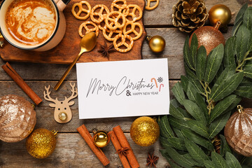 Beautiful Christmas composition with greeting card, decor and mug of coffee on wooden background