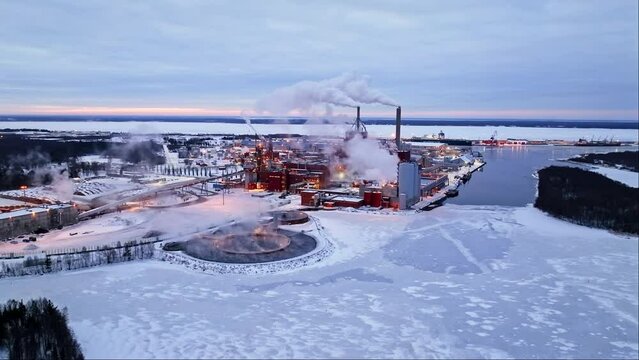 Establishing drone shot toward a large pulp mill factory, winter morning in Oulu