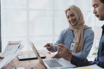 Fototapeta premium Group of young Asian business people talk, consult, discuss working with new startup project idea presentation analyze plan marketing and investment.