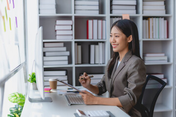 Asian businesswoman smiling using laptop computer at office. Confident Asia businesswoman sitting happily in the office.