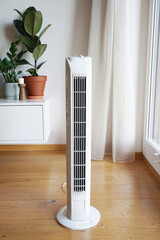 White tower vertical fan on wooden floor in modern interior