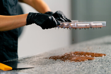 Drops of melted hot chocolate that pours out of an inverted mold for making candies in...