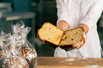 close-up of female hands holding freshly cut Easter loaf with raisins dried apricots and almonds - obrazy, fototapety, plakaty