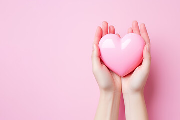 hand holds a heart love shape on a pink background with copy space