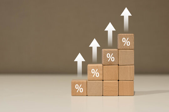 Wooden blocks with icon percentage and arrow pointing up. Interest rate financial and mortgage rates concept.