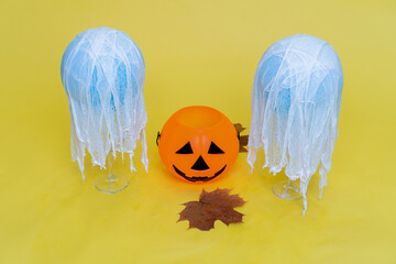 Halloween ghosts made from bandages, glue, water and using balloons and glasses on yellow orange...