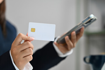 Close up businesswoman hand holding credit card and smartphone, doing online purchases or paying online
