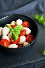 Mozzarella with cherry tomatoes with basil on a dark gray background
