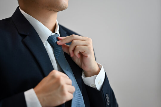 Close up of a businessman in formal clothes adjusting his necktie on white background