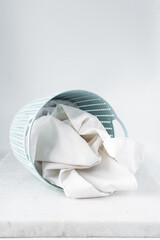 Blue laundry basket with linens inside, Woven plastic laundry hamper with a white background