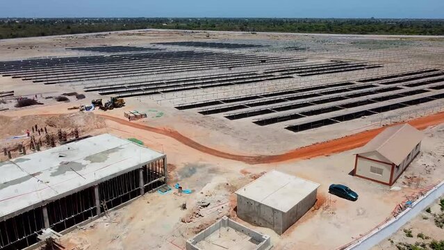 Aerial view of photovoltaic power plant with buildings and solar panels under construction in Jambur, Gambia