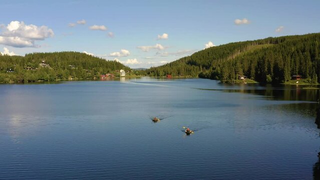 Two packrafts paddling on Mylla Lake surrounded by forest on stunning day, drone