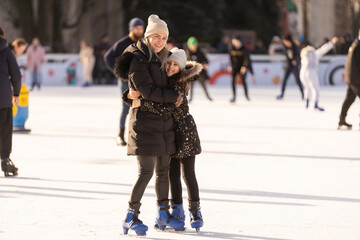 Action shot of beautiful woman teaching her daughter how to ice skate