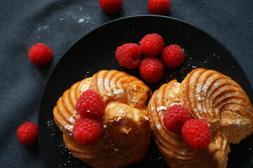 Cakes with raspberries on a black plate on a dark background