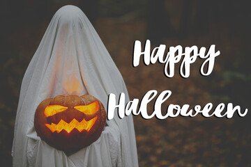Happy Halloween! Happy Halloween text and spooky ghost holding glowing jack o lantern in moody dark autumn forest. Scary atmospheric halloween greeting card, handwritten sign. BOO!