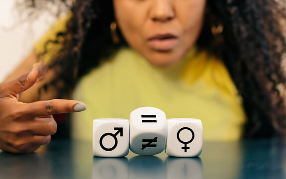 Symbol for gender equality. Women pointing to dice with the unequal and equal sign between symbols of men and women..