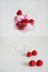 Strawberry and vanilla ice cream with raspberries in a glass on a white background
