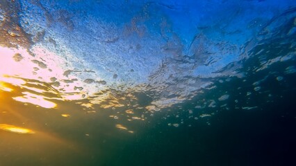 Sunset sun rays shining through clear sea water. Underwater shot from sea bottom on the sunrise sky - Powered by Adobe