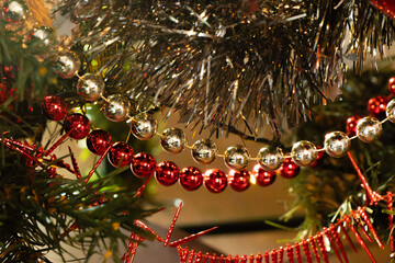Detail of Christmas ornaments. Tinsel and pearl garlands in red and gold colors. Close up. Selective focus