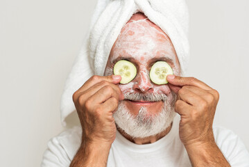 Senior man with towel on head doing facial beauty care