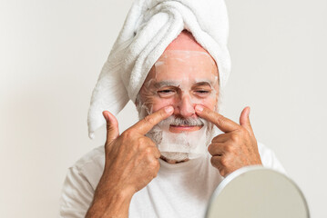 Elderly man applying facial mask after shower
