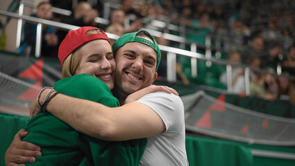 Love couple hug at sport stadium. Happy fans look camera. Romantic date together. Smiling beauty...