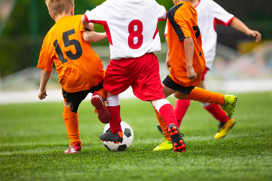 Young boys playing football game on a school tournament. Football soccer match for children. Dynamic, action picture of kids competition during playing football