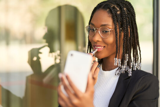 Black Businesswoman Using Smartphone As Mirror Doing Makeup