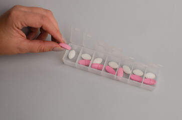 Close-up of unrecognizable girl sorting vitamins into pill organizer , biohacking concept