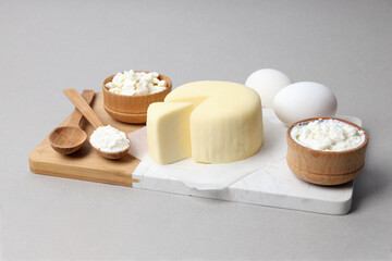 Dairy products on a wooden board, on a gray background.