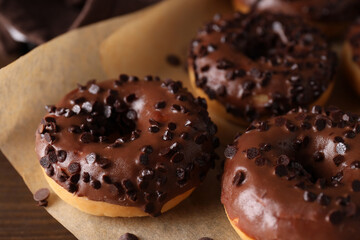 Chocolate donuts on parchment, on the table.